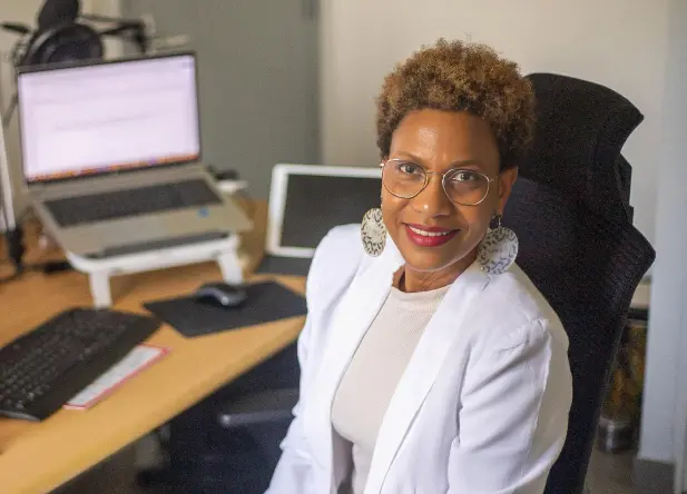 Photo de Micheline Boutrin Deroire prise dans son espace de travail. Cette image accompagne un bilan de mi-année, centré sur la transformation, les ajustements et les réalignements vécus. Portrait de Micheline Boutrin Deroire dans son bureau, en posture posée et authentique, pour illustrer un bilan personnel et professionnel.
